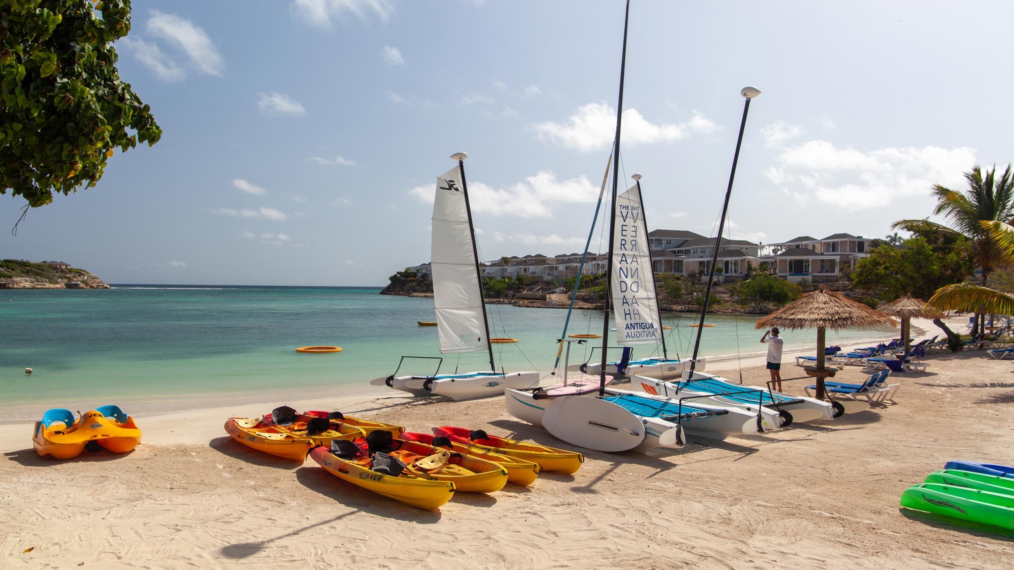 Kayaks and sail boats lined up on a beach in Antigua