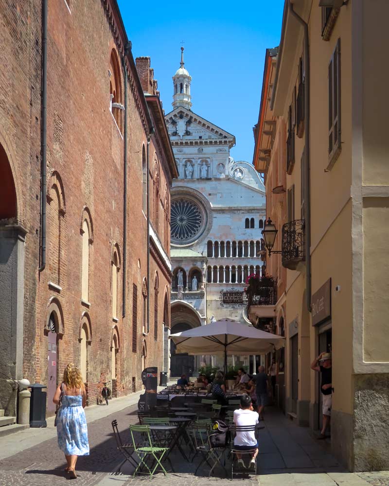 The Cremona Cathedral framed by a restaurant on one side and the town hall on another