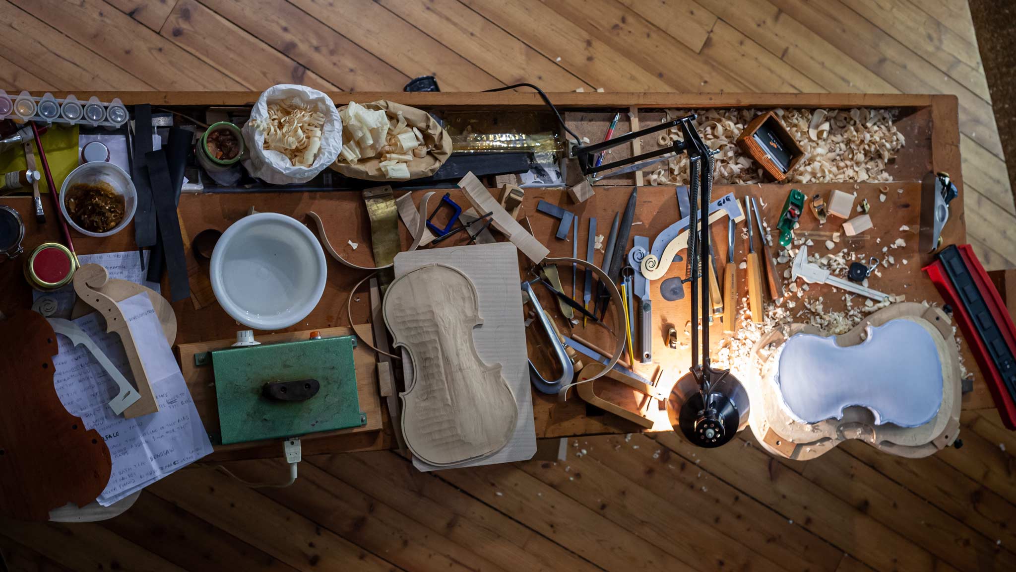 Looking down on a table where Violins are made full of various tools in Cremona