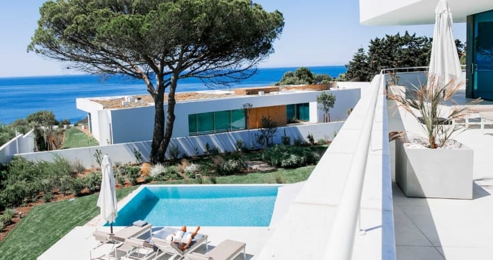 Looking out on the Atlantic ocean and an infnity pool with two white luxury villas in the picture at Lux Mare