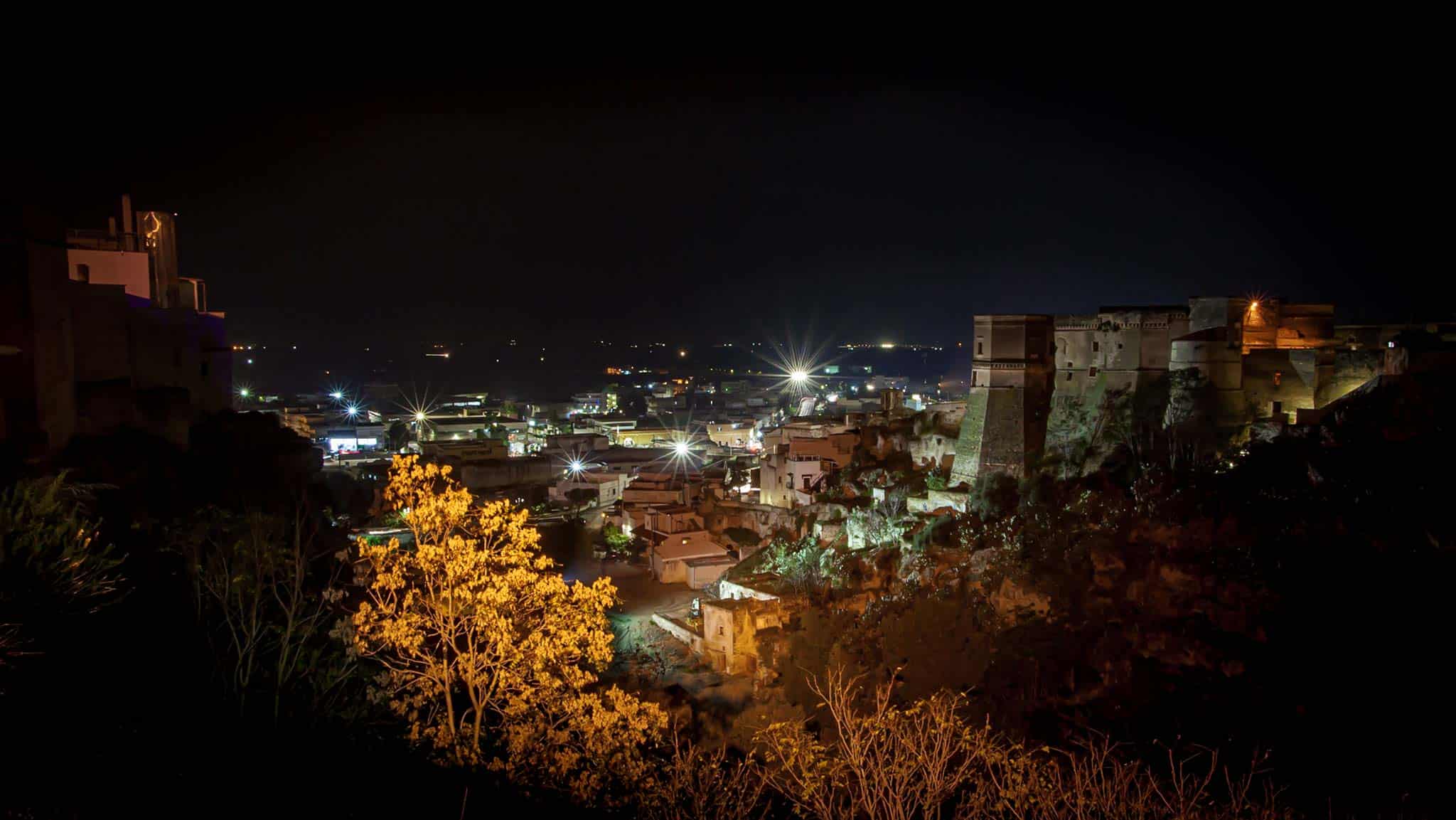At night the castle on the right sits above the Puglia town below 