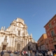 The main square in Murcia with a cathedral on the left and a red fronted palace on the right