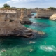 Blue hued waters crash into rocks jutting out of the Puglia coastline