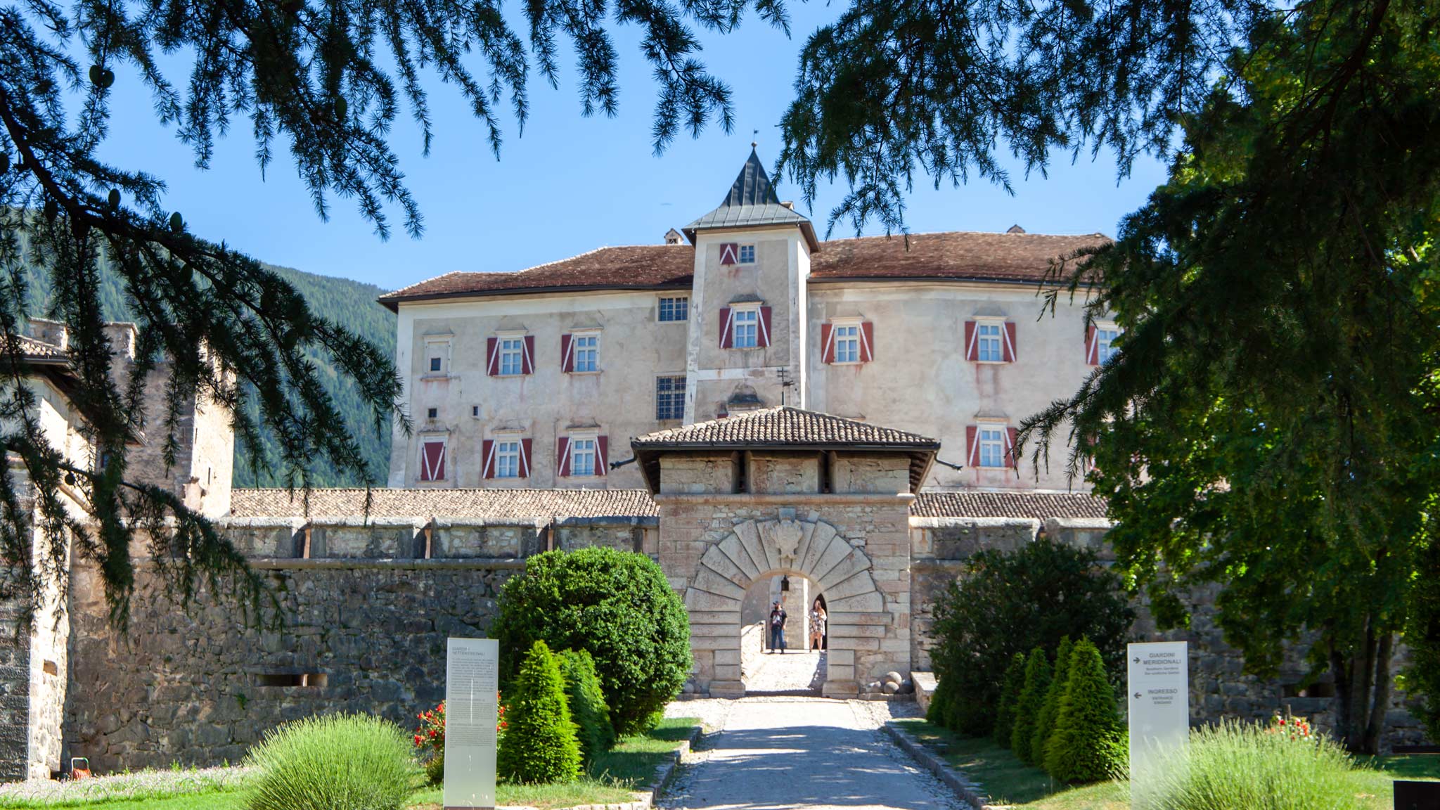 Castel Thun in its wonky glory as framed by trees outside 