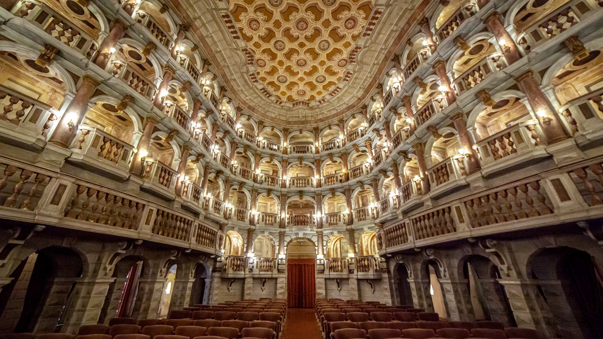 A grand theatre, looking out from the stage to the stools and boxes in Mantua 