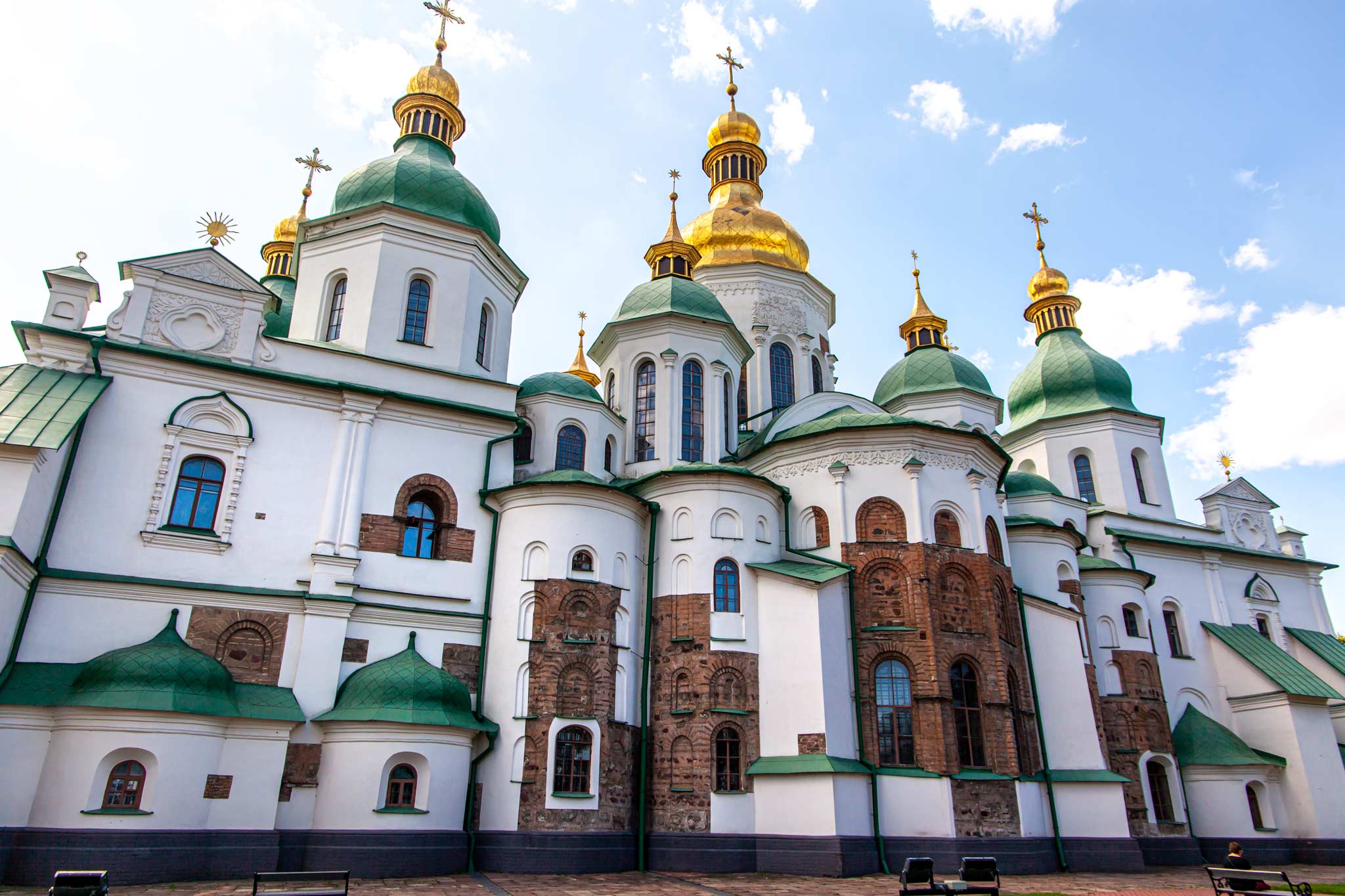 A green and white Kyiv orthodox cathedral with gold domes on the roof