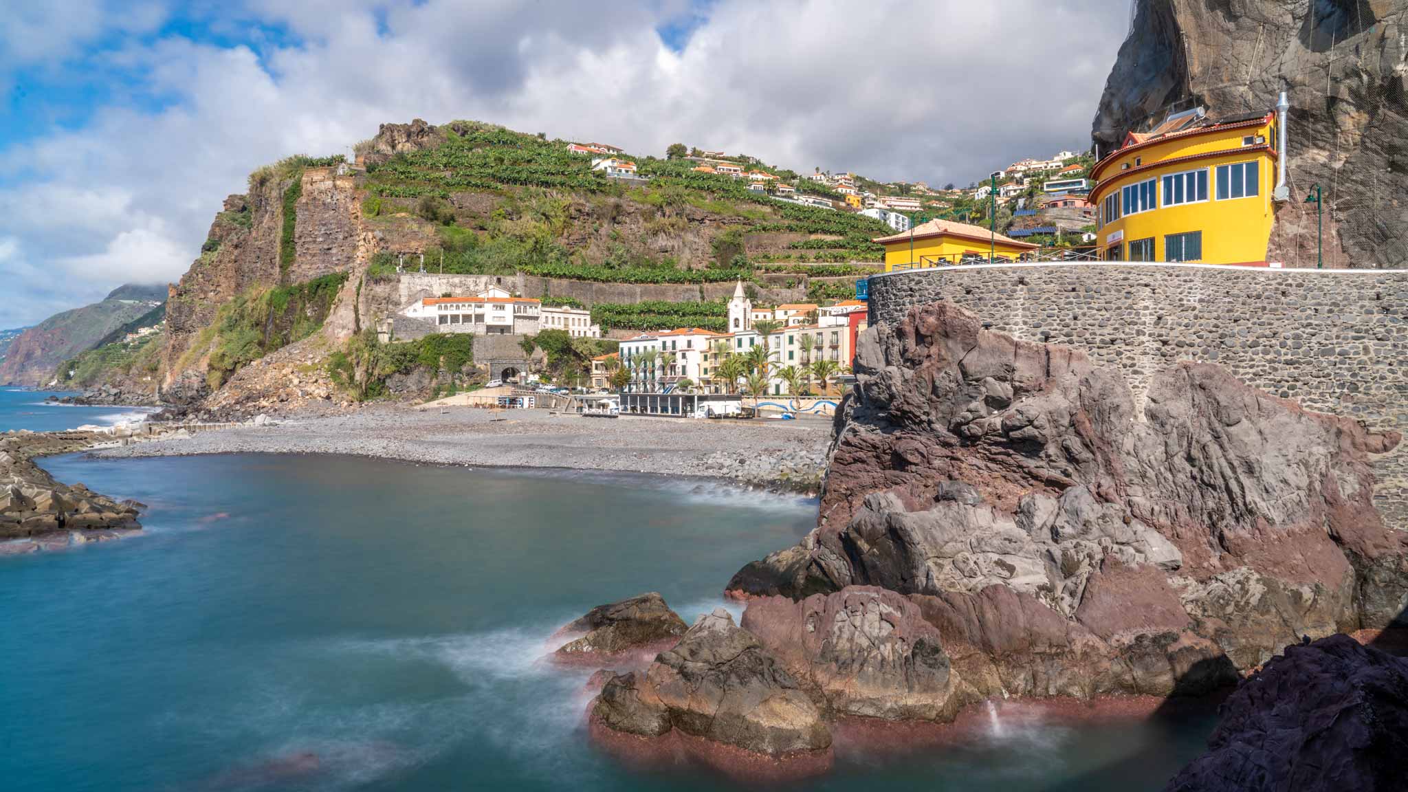 The village of Ponto do Sol in Madeira, with green hills and a small bay for swimming