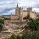 The Alcazar of Segovia on a cloudy day perches on a hill