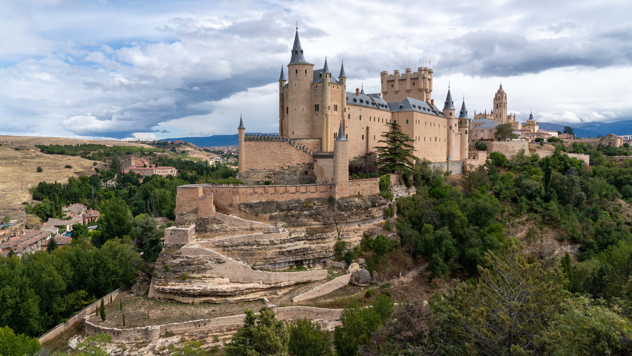 The Alcazar of Segovia on a cloudy day perches on a hill