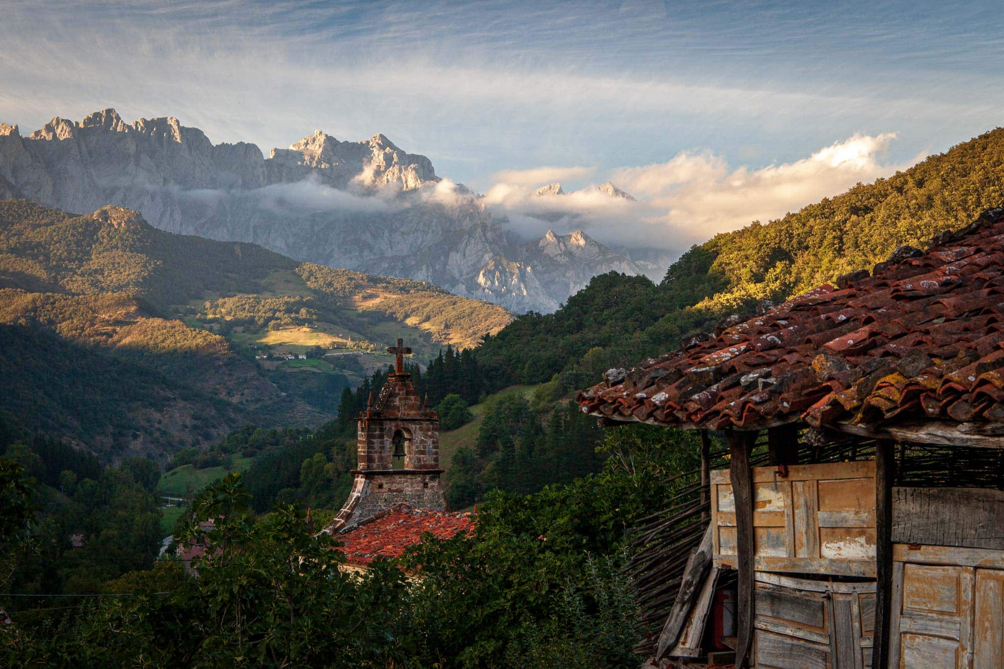 The mountains of Picos de Europa at sunset with an old stone house in the foreground