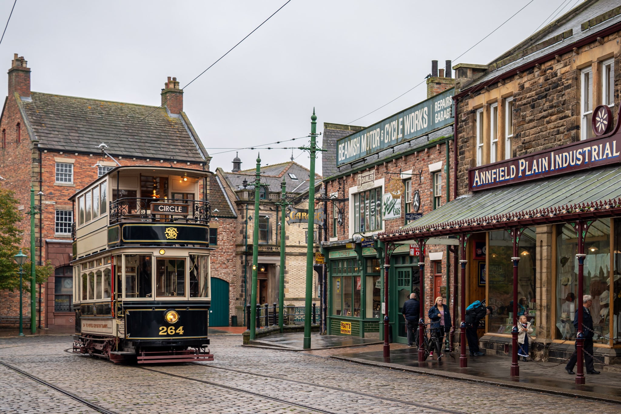 A vintage tram passes by old-style Victorian shops with wooden signs and porches